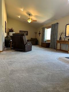 carpeted living room with a ceiling fan and vaulted ceiling