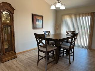 dining room with vaulted ceiling, wood finished floors, baseboards, and a notable chandelier