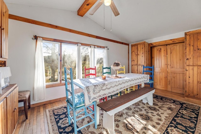 dining room with light wood finished floors, a ceiling fan, and vaulted ceiling with beams