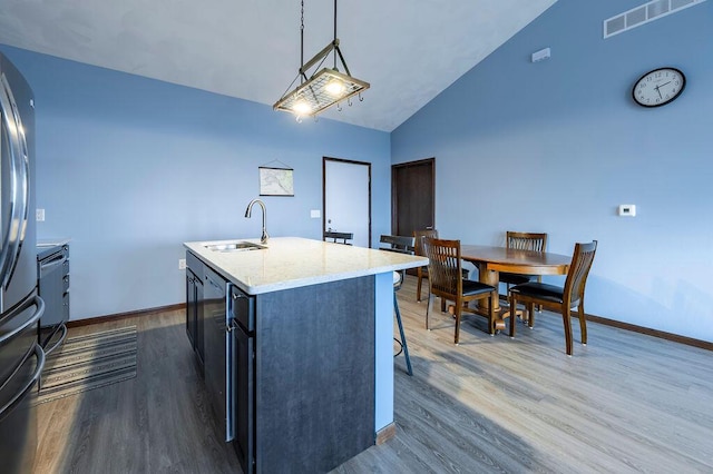 kitchen featuring baseboards, dark wood-style flooring, visible vents, a sink, and an island with sink