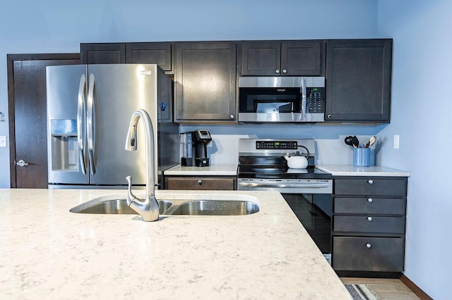kitchen featuring light stone counters, appliances with stainless steel finishes, and a sink