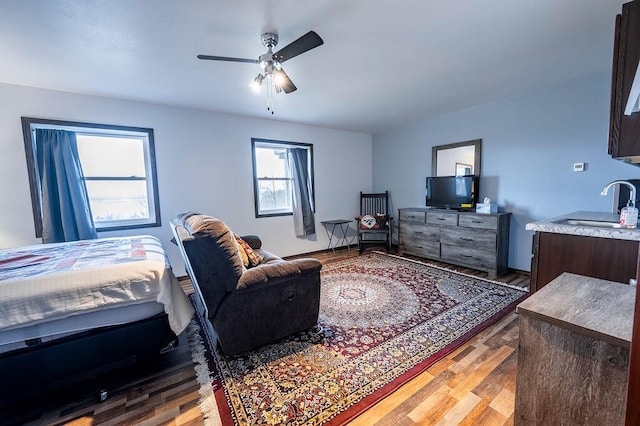 bedroom featuring ceiling fan, light wood-type flooring, and a sink