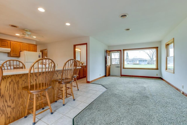 W10940 W Harmony Dr, Lodi, WI 53555 - kitchen with freestanding refrigerator, a breakfast bar area, light colored carpet, baseboards, and recessed lighting