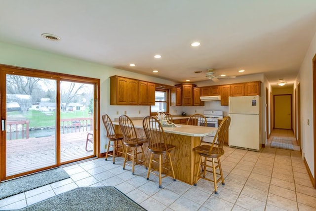 W10940 W Harmony Dr, Lodi, WI 53555 - kitchen featuring white appliances, under cabinet range hood, a peninsula, recessed lighting, and light tile patterned floors
