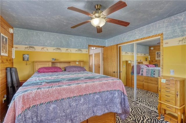 bedroom with ceiling fan, a closet, and wallpapered walls
