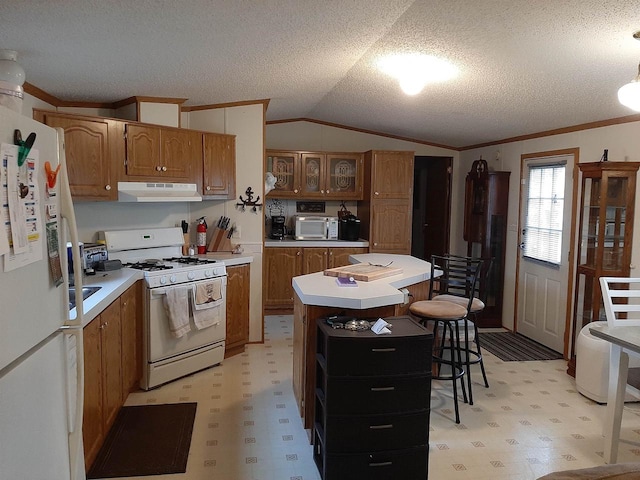 kitchen with brown cabinets, white appliances, light countertops, and under cabinet range hood
