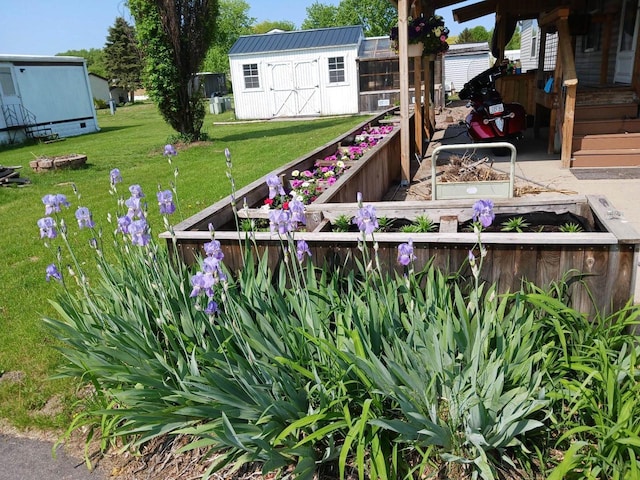 view of yard featuring fence, a storage shed, a garden, and an outdoor structure