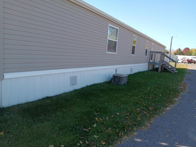 view of side of home with a yard and central AC