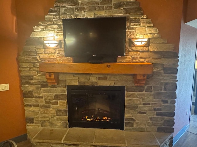 details with wood finished floors and a stone fireplace
