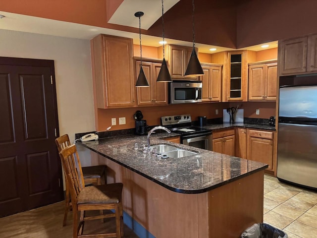 kitchen with a peninsula, glass insert cabinets, a sink, stainless steel appliances, and a kitchen breakfast bar