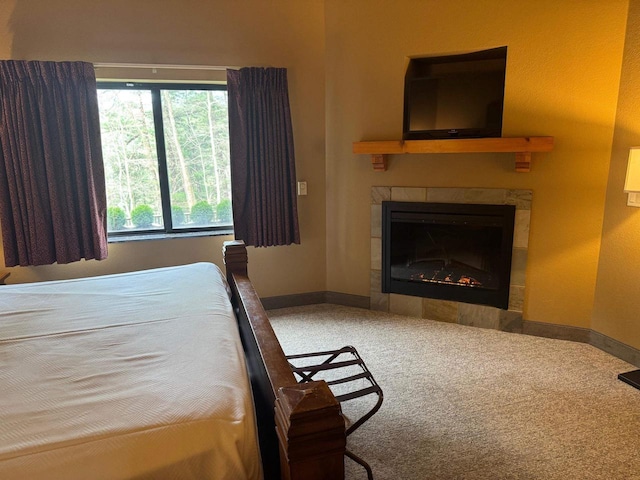 bedroom with baseboards, a tile fireplace, and carpet
