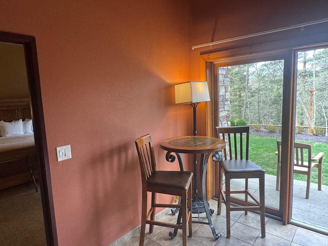 tiled dining area featuring a healthy amount of sunlight and a textured wall