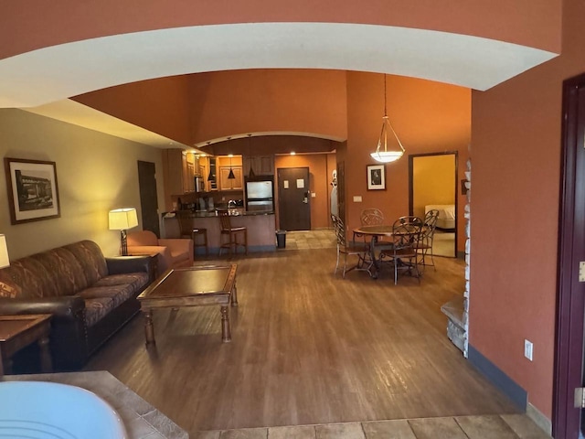 living area with arched walkways, baseboards, and wood finished floors