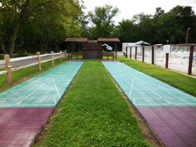 surrounding community with shuffleboard, a yard, and fence