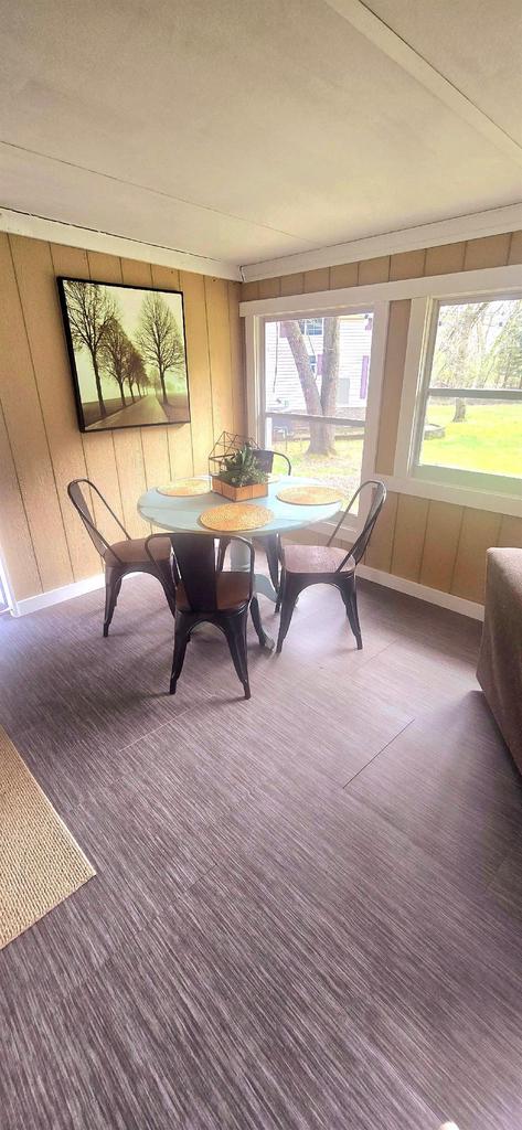 carpeted dining area featuring wood walls, baseboards, and plenty of natural light