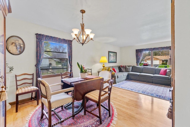dining space featuring a wealth of natural light, a notable chandelier, and light wood-type flooring