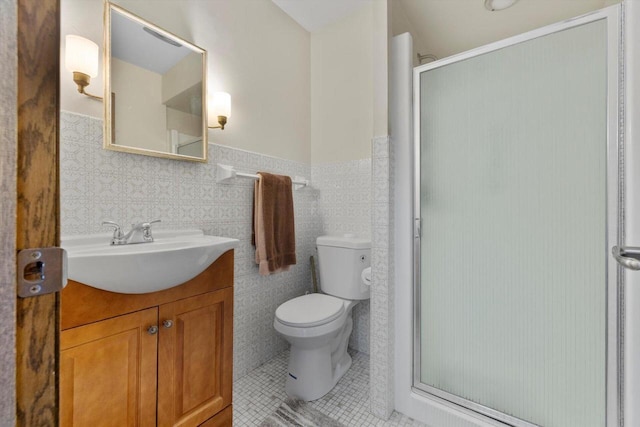 bathroom with toilet, tile patterned floors, wainscoting, a shower stall, and vanity