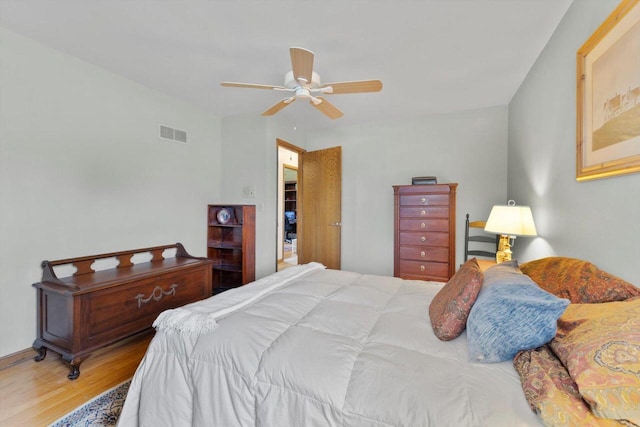 bedroom featuring a ceiling fan, visible vents, and wood finished floors