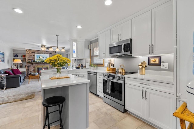 kitchen featuring stainless steel appliances, a breakfast bar, white cabinetry, open floor plan, and light countertops
