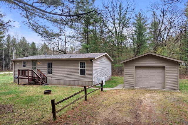 view of front of home with driveway, an outbuilding, a detached garage, an outdoor fire pit, and a front lawn
