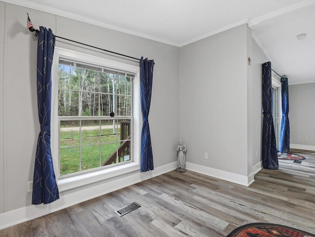 unfurnished room featuring baseboards, ornamental molding, visible vents, and wood finished floors
