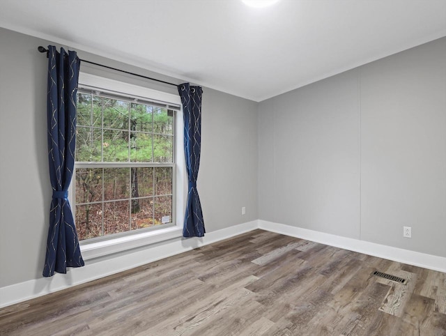 empty room featuring baseboards, visible vents, and wood finished floors