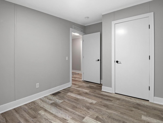 unfurnished bedroom featuring baseboards, visible vents, and wood finished floors
