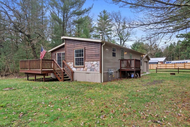 back of house featuring a deck, fence, and a lawn