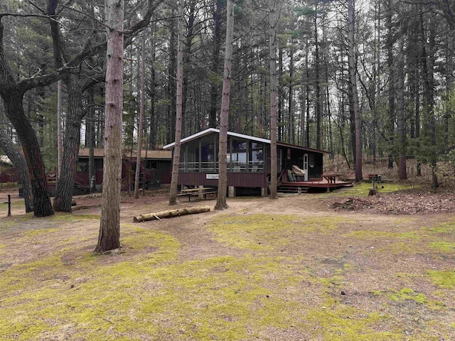 exterior space with a sunroom, a view of trees, and a wooden deck