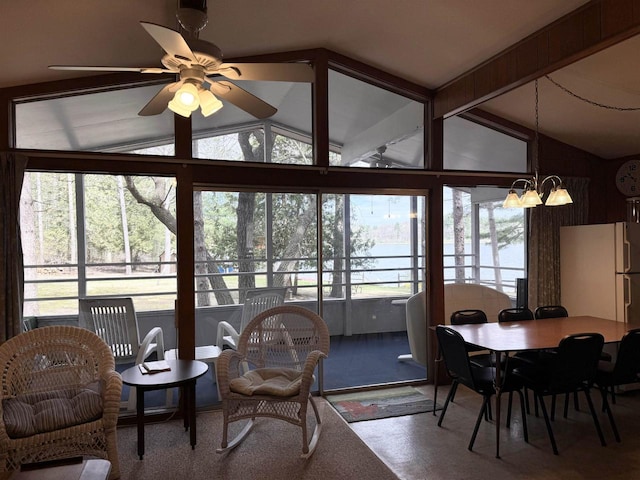 dining space with a water view, lofted ceiling, a wealth of natural light, and ceiling fan with notable chandelier