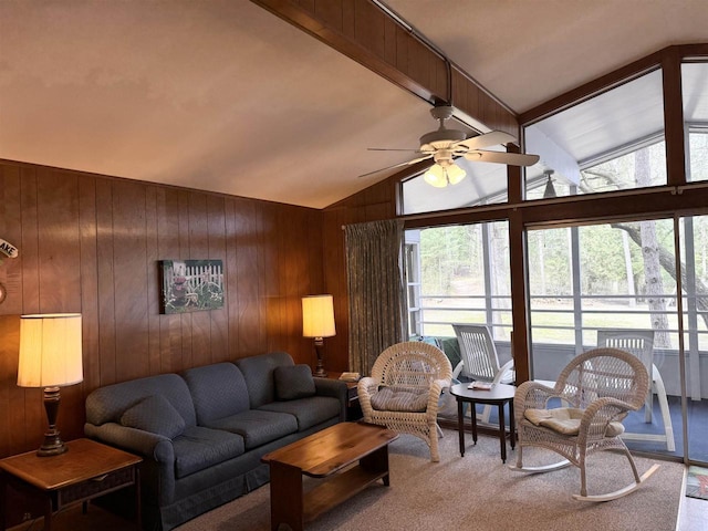 living area featuring a ceiling fan, wooden walls, lofted ceiling, and a healthy amount of sunlight