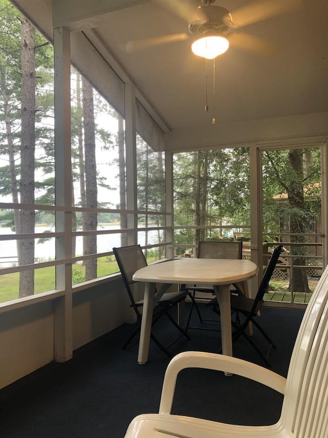 sunroom with a water view, outdoor dining space, and ceiling fan