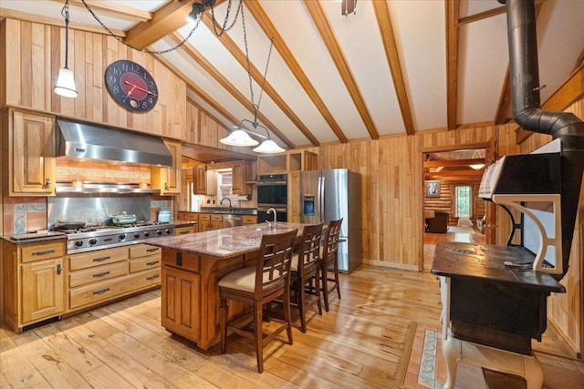 W2470 County Road B, Montello, WI 53949 - kitchen featuring appliances with stainless steel finishes, wall chimney exhaust hood, wooden walls, light wood finished floors, and a kitchen bar