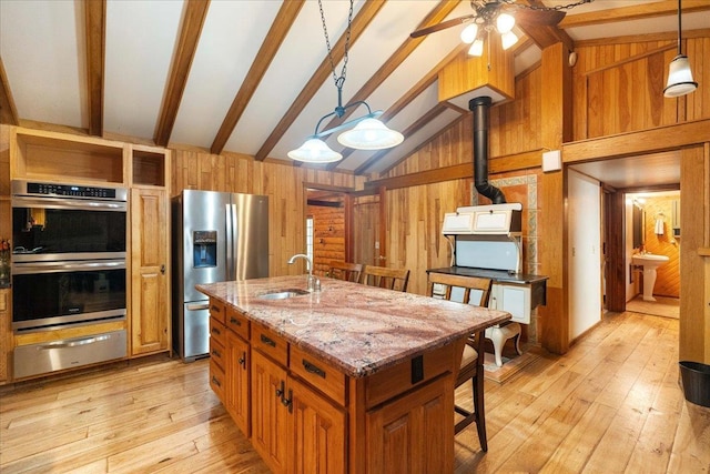 W2470 County Road B, Montello, WI 53949 - kitchen with a warming drawer, stainless steel appliances, wooden walls, a sink, and brown cabinets