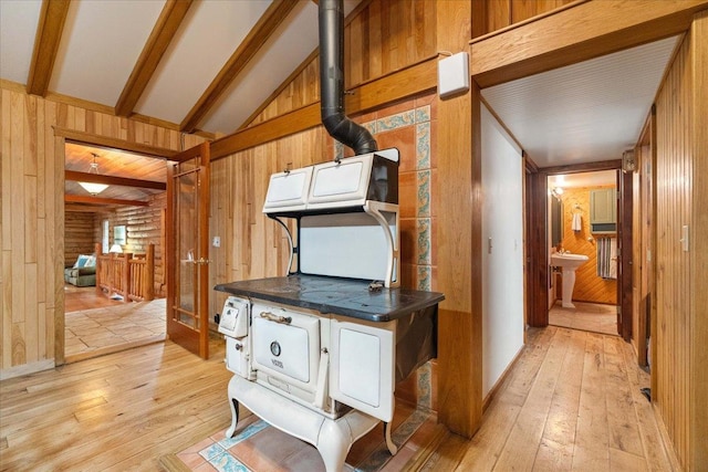 W2470 County Road B, Montello, WI 53949 - kitchen featuring light wood-style floors, a wood stove, wooden walls, dark countertops, and brown cabinetry