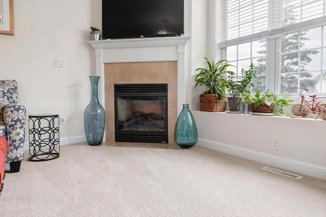 interior space featuring carpet, a tiled fireplace, visible vents, and baseboards