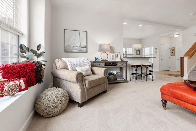 living room featuring light carpet, baseboards, and stairway