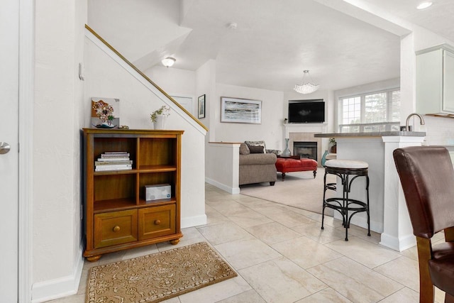 living area with baseboards, stairs, and a fireplace
