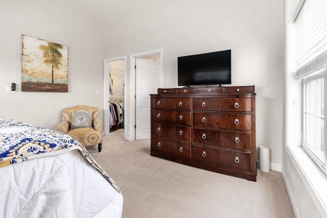 bedroom featuring light colored carpet and a walk in closet