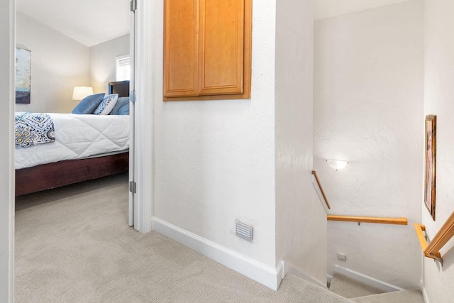interior space featuring baseboards, an upstairs landing, visible vents, and light colored carpet