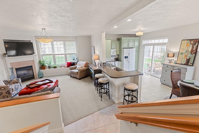 living room with a textured ceiling, light colored carpet, a tile fireplace, and plenty of natural light