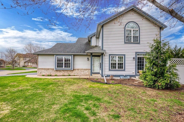 traditional home featuring fence, brick siding, and a front yard