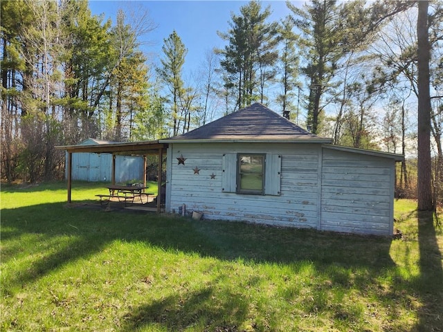 view of side of home featuring a lawn and an outbuilding
