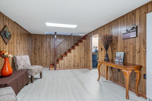 sitting room with stairway, wood walls, and light wood-style floors