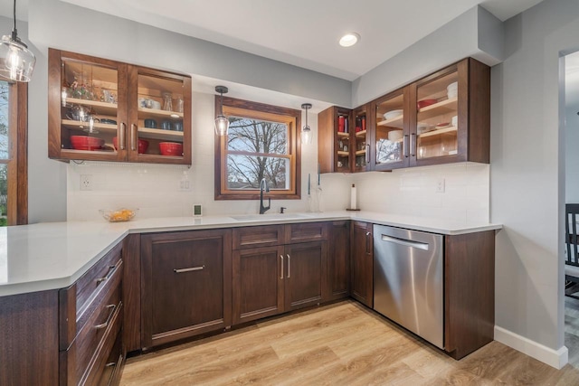 kitchen with light wood finished floors, backsplash, stainless steel dishwasher, and a sink