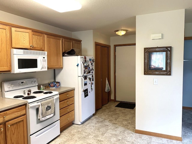 kitchen with baseboards, brown cabinets, white appliances, and light countertops