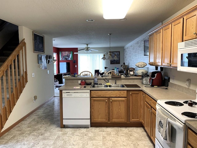 kitchen with brown cabinetry, white appliances, ceiling fan, a sink, and a peninsula