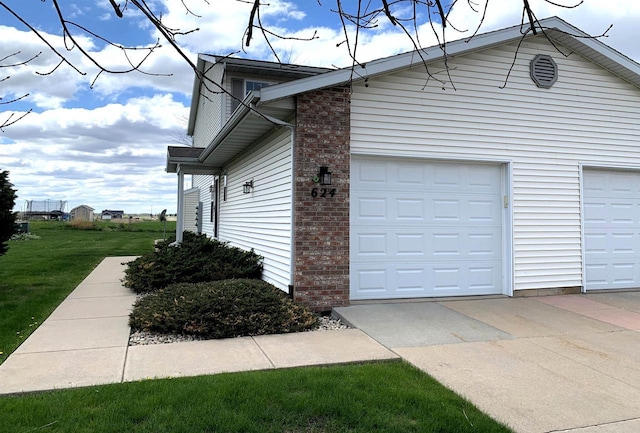 view of property exterior featuring a yard, brick siding, and a garage