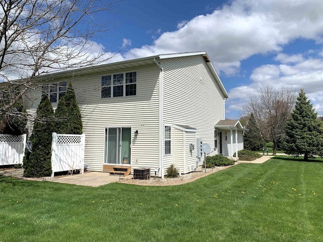 back of house with central air condition unit, a yard, and fence