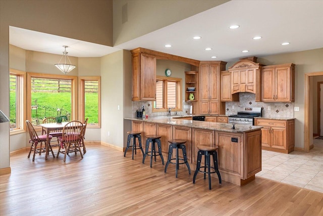 kitchen featuring stainless steel gas range, light wood finished floors, a sink, and recessed lighting